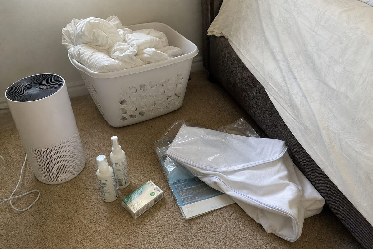 Washed sheets, purifier, spray bottle and vacuum beside a bed